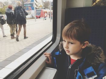 Cute boy looking away while sitting in train