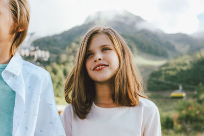 Smiling sibling standing against mountain