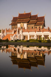 Traditional building by lake against sky in city