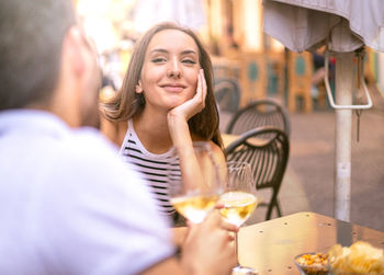 Smiling woman with man sitting at sidewalk cafe