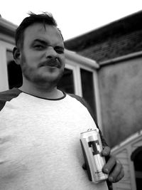 Portrait of young man standing against house