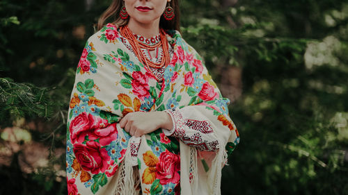 Portrait of young woman standing against trees