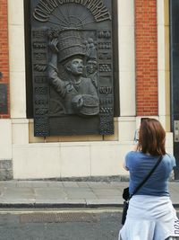 Rear view of woman standing against wall