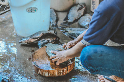 Midsection of man cutting fish in market