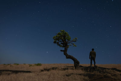 Rear view of man on field against sky at night