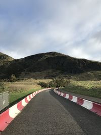 Empty road by mountain against sky