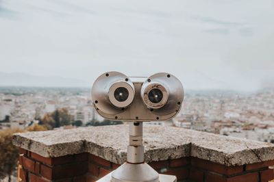 Close-up of coin-operated binoculars against buildings in city