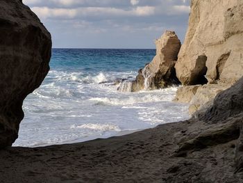 Rock formation on beach against sky