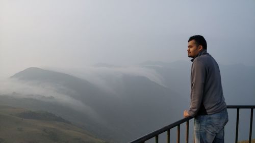 Man at observation point overlooking landscape during foggy weather