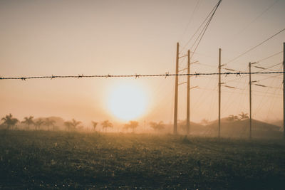 Electricity pylon on field against sky during sunset