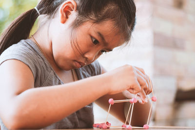 Cute girl making molecule model on wooden table in porch