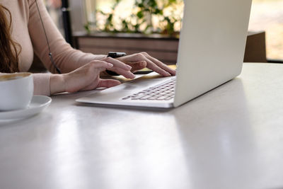 Close-up of man using laptop on table