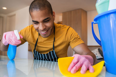Portrait of smiling young man holding table at home