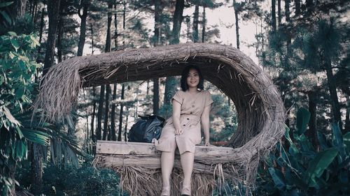 Portrait of young woman sitting under hay shelter in forest