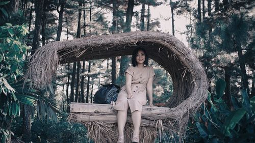 Portrait of young woman sitting on tree in forest