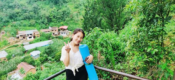 Young woman smiling while sitting on land against trees