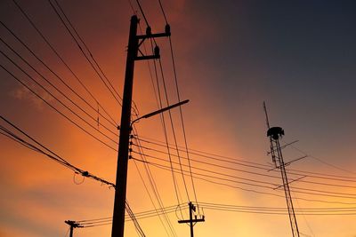 Low angle view of silhouette electricity pylons against sky during sunset