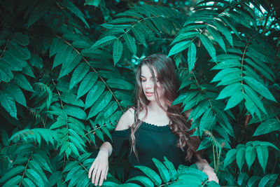 Smiling young woman standing amidst plants