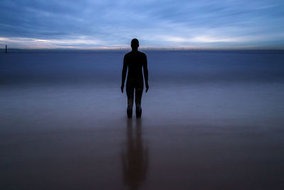 Rear view of silhouette man standing on beach