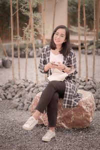 Portrait of young woman sitting on retaining wall