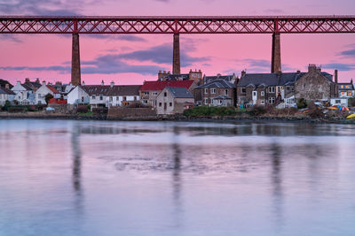 River by buildings against sky at dusk