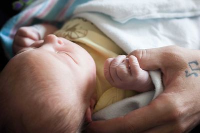 Close-up of baby girl holding father thumb in hospital