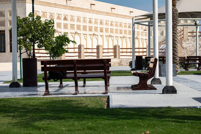 Empty bench in park against buildings in city