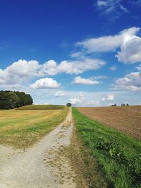 Scenic view of country road against cloudy sky