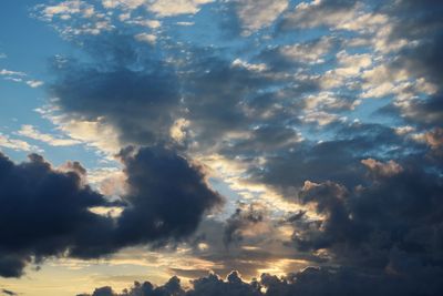 Low angle view of sunlight streaming through clouds