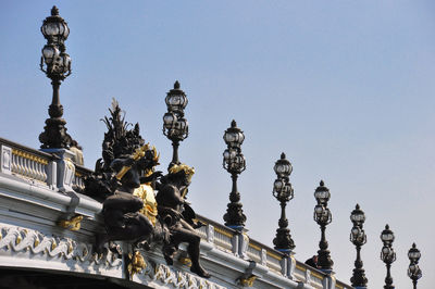 Low angle view of statues on pont alexandre iii against clear sky in city