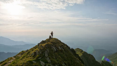 Man standing on rock against sky