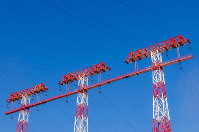 Low angle view of electricity pylon against clear blue sky