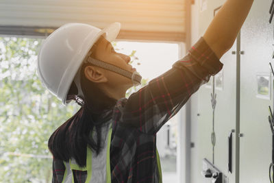 Low angle view of female worker wearing hardhat with arms outstretched