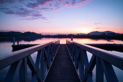 Pier over lake against sky during sunset