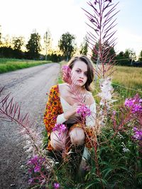 Portrait of woman sitting on pink flower in field