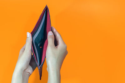 Close-up of hand holding orange against yellow background