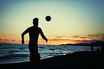 Silhouette of people on beach at sunset