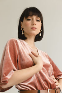 Portrait of beautiful young woman standing against gray background