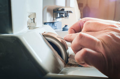 Hands of a man sharpening a needle on a grinding wheel