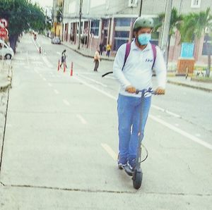 Full length of man skateboarding on street in city