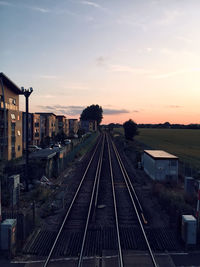 Train on railroad tracks against sky during sunset