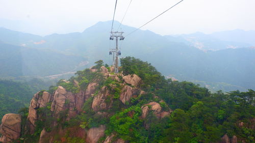 Overhead cable car on mountains against sky