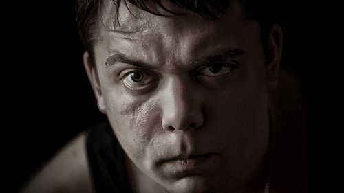 Portrait of angry man against black background