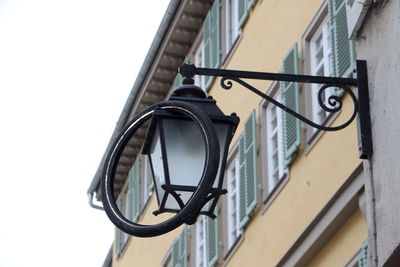 Low angle view of tire hanging from gas light against building