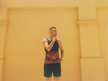 Man smoking while standing against wall