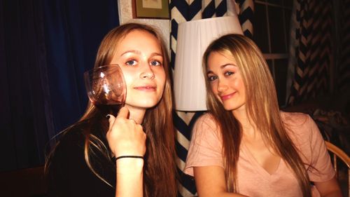 Portrait of smiling friends sitting on chair at restaurant