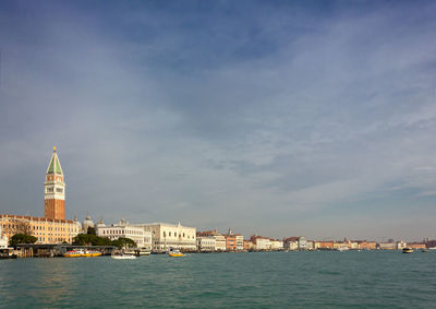 View of buildings at waterfront against cloudy sky