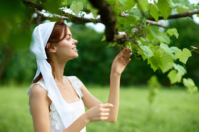 Side view of young woman holding flowers