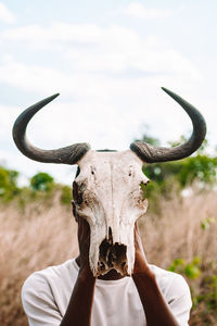 Portrait of a young adult holding a buffalo head skeleton 