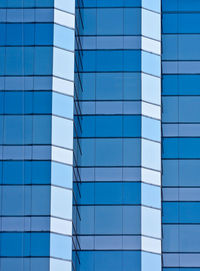 Low angle view of glass building against blue sky